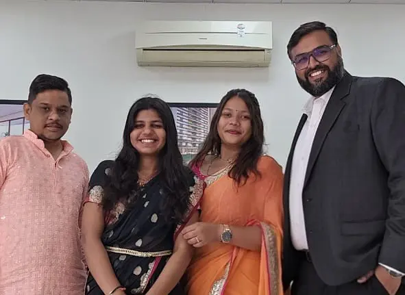 Group of five GIAS staff in black, red, waistcoat, and pink/purple traditional wear.
